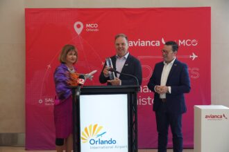Avianca and MCO officials holding a trophy and model aircraft in front of banners celebrating 15 years of operations