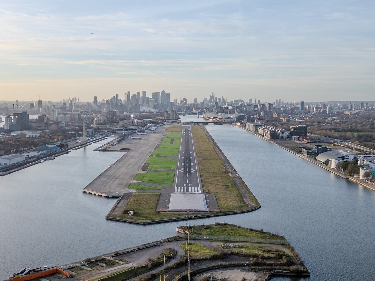 A sky picture of London City Airport. One can see the river Thames surrounding the airport's runway.
