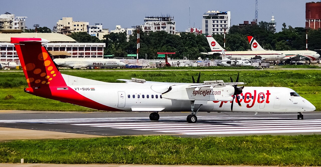 A SpiceJet Dash 8 Q 400 Aircraft resting on tarmac with grass around it
