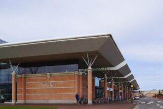 The outside of terminal at Jersey Airport. The sky is very cloudy with the blue sky peeking through