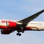 Side view of the full length of Air India's VT-ANT with its landing gear extended in the sky.