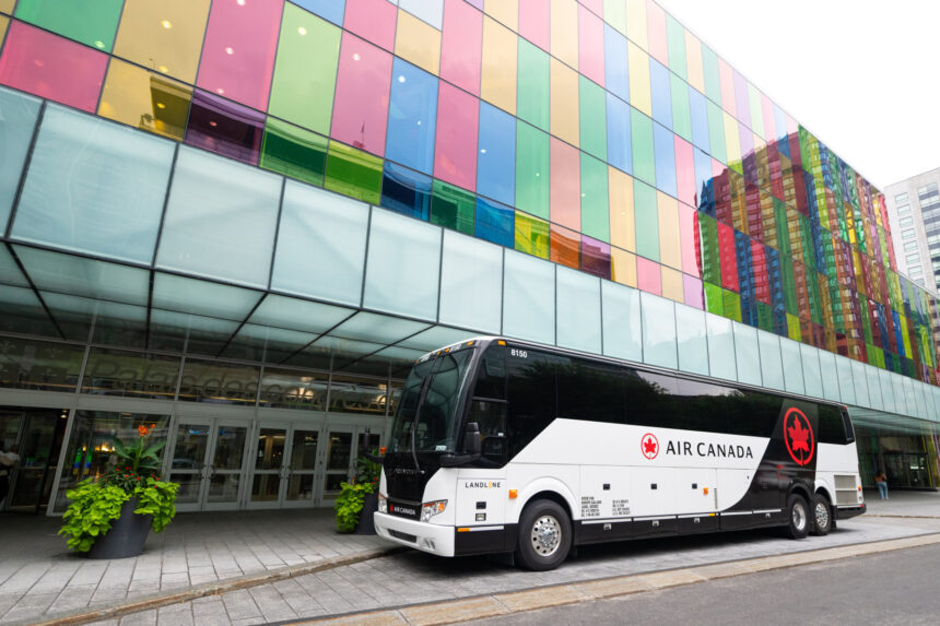 Air Canada branded coach, red and white, parked on a road in front of a colourful building.
