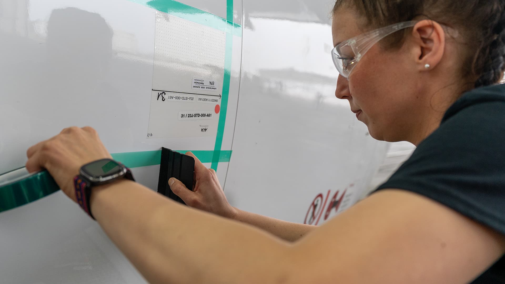 Lady applying the shark skin tape onto the aircraft 