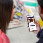 A man and woman, with only the backs of their heads showing, are holding and looking at a phone