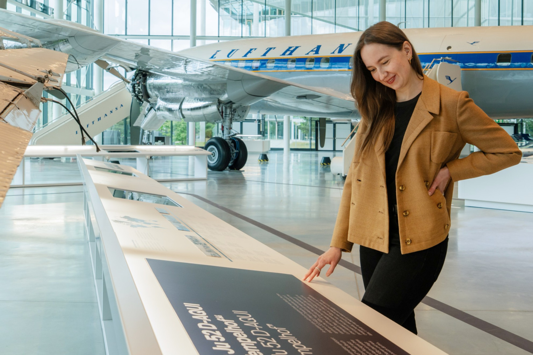 lady stands reading an information board with an aircraft exhibited in the background