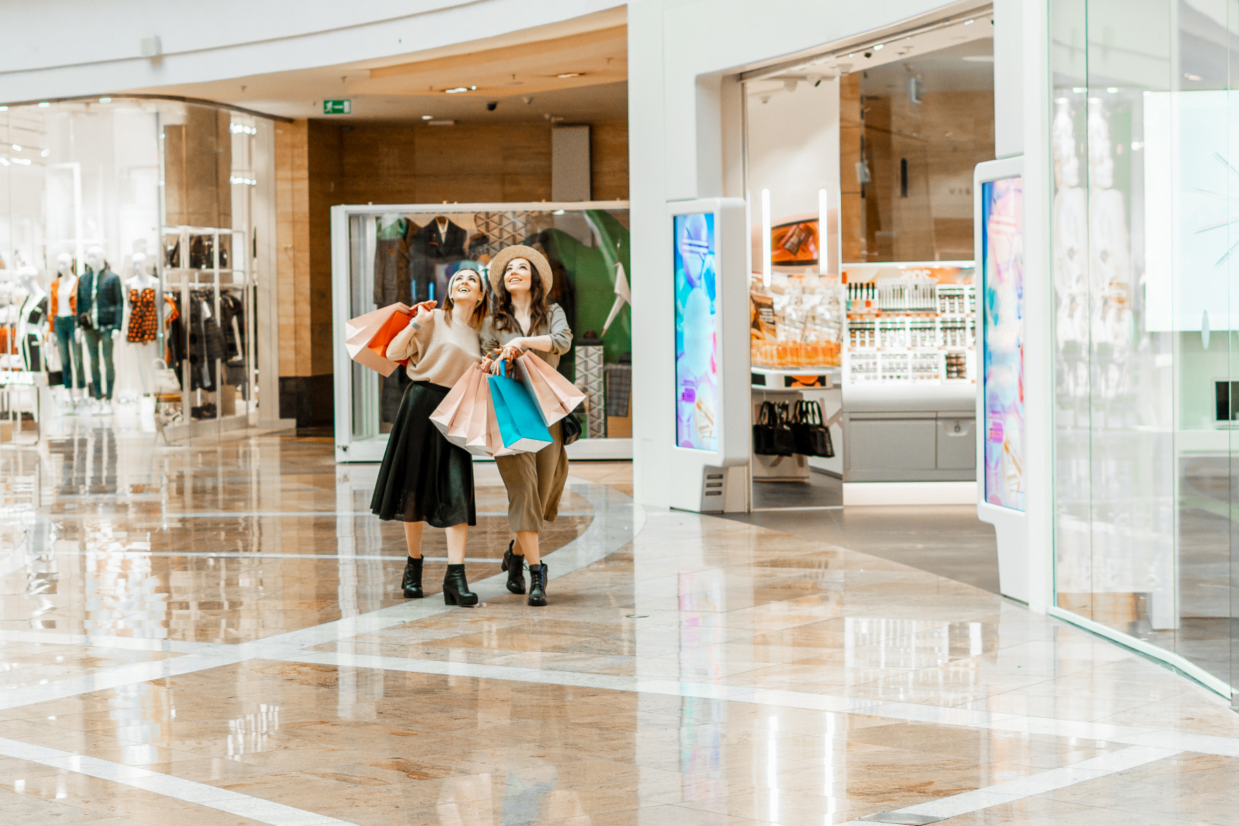 Two female shoppers in a mall carrying shopping bags