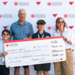 People holding a large cheque in front of Air Canada signage showing $1.5 million raised. Two adults and two children with Air Canada Foundation lanyards.