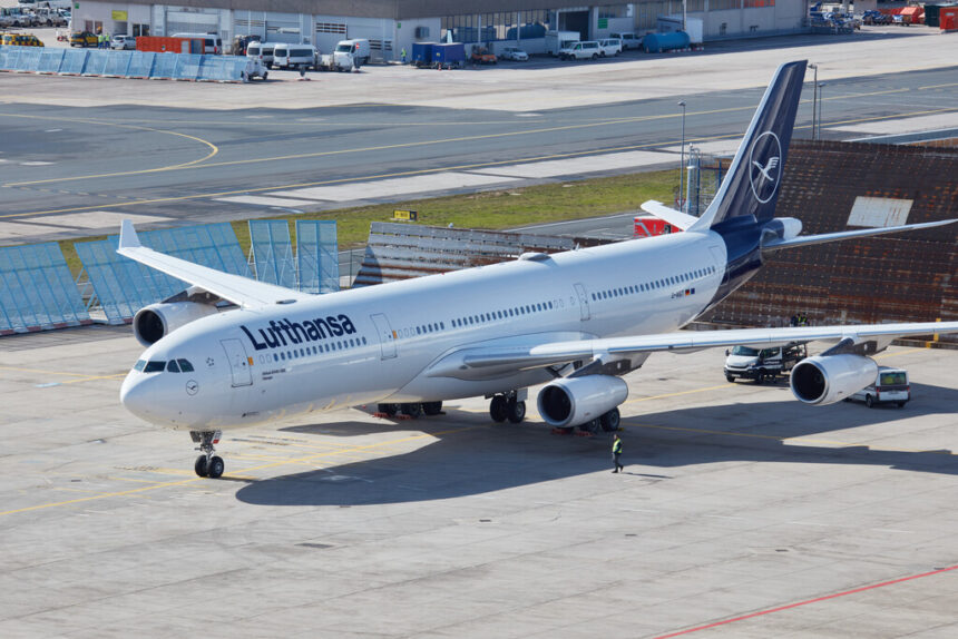 Image shows a Lufthansa Airbus A340-300 aircraft with white and blue livery, grounded at an airport during the day