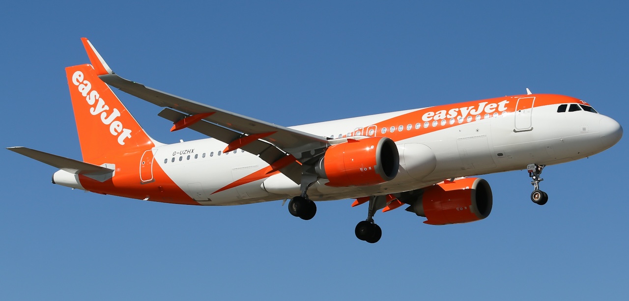 easyJet's G-EZTY in the sky with its landing gear extended. Both engines below the wings are visible.