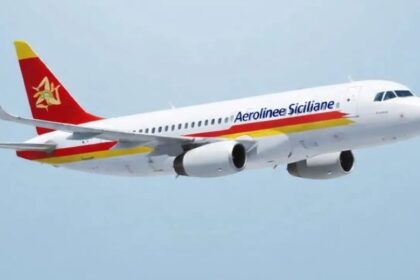 An Aerolinee Siciliane aircraft flying in the blue sky. White, red and yellow livery.
