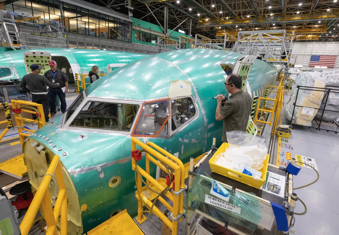 Boeing employees assembling a 737 MAX aircraft on a moving production line at the Everett plant