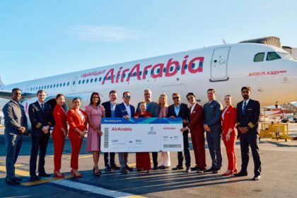 An image of Gatwick and Air Arabia employees holding a large boarding pass standing in front of a Air Arabia aircraft