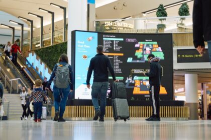 Image shows London Gatwick Airport with screens and passengers with baggage