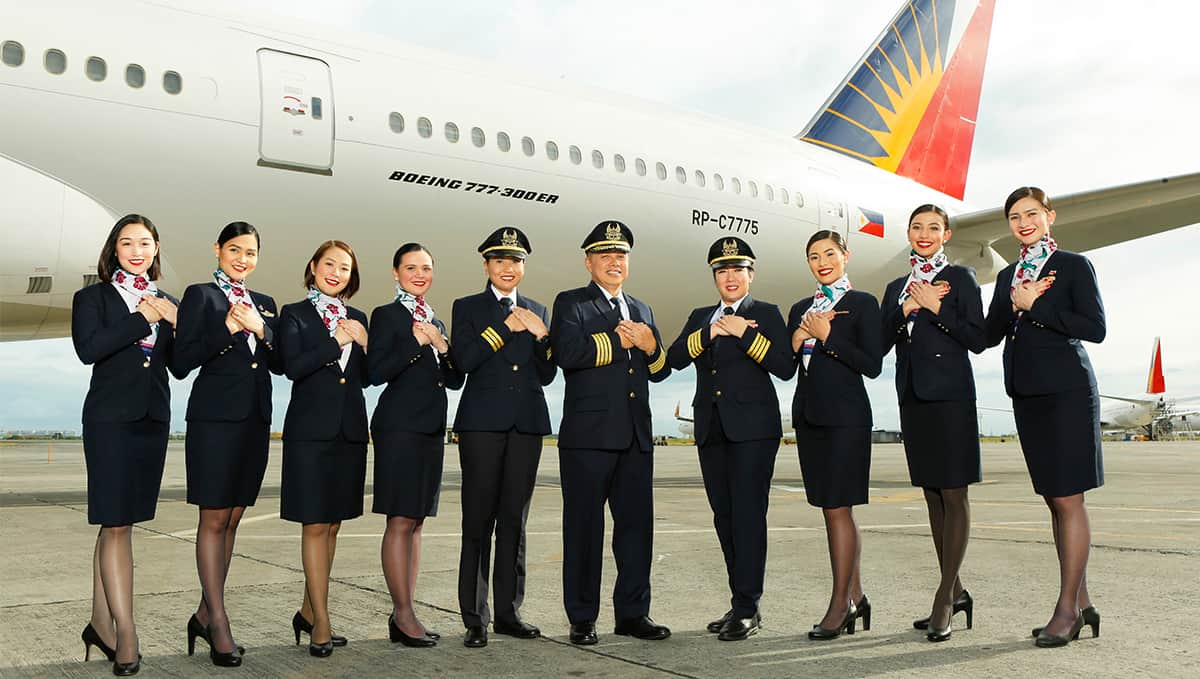 Philippine Airlines staff stand infront of a branded 777-300 in uniform