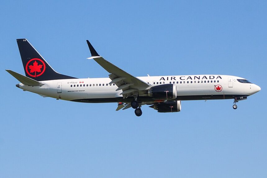 An Air Canada Boeing 737 MAX 8 (registration C-FSJG) on approach with landing gear extended, set against a clear blue sky, showcasing the airline's livery with a white upper fuselage, dark blue belly and tail, and the iconic red maple leaf logo.