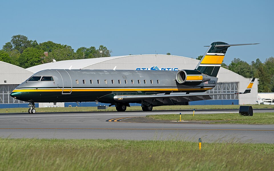 A private Bombardier Global Express business jet (N101CN) featuring a silver, dark green, and yellow livery taxiing along the tarmac at Westchester County Airport (KHPN) under a bright, sunny sky.