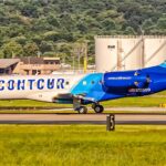 Side profile view of a Contour Airlines Embraer ERJ-135ER (registration N15509) taxiing on the airport runway with fuel storage tanks in the background.