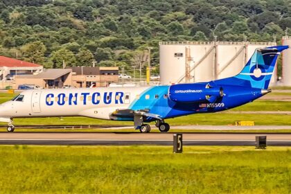 Side profile view of a Contour Airlines Embraer ERJ-135ER (registration N15509) taxiing on the airport runway with fuel storage tanks in the background.
