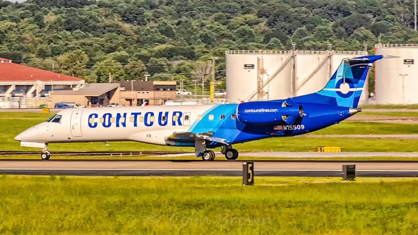 Side profile view of a Contour Airlines Embraer ERJ-135ER (registration N15509) taxiing on the airport runway with fuel storage tanks in the background.