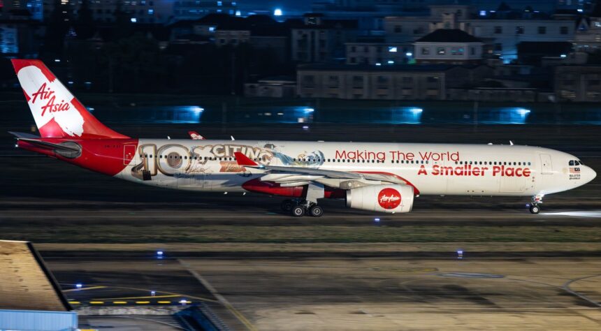 AirAsia X Airbus A330-343, registration 9M-XXF, in 10th anniversary livery reading "Making The World A Smaller Place," landing at night.