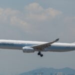 A Cathay Pacific Airbus aircraft taking off at Hong Kong International Airport. Cloudy sky in the background.