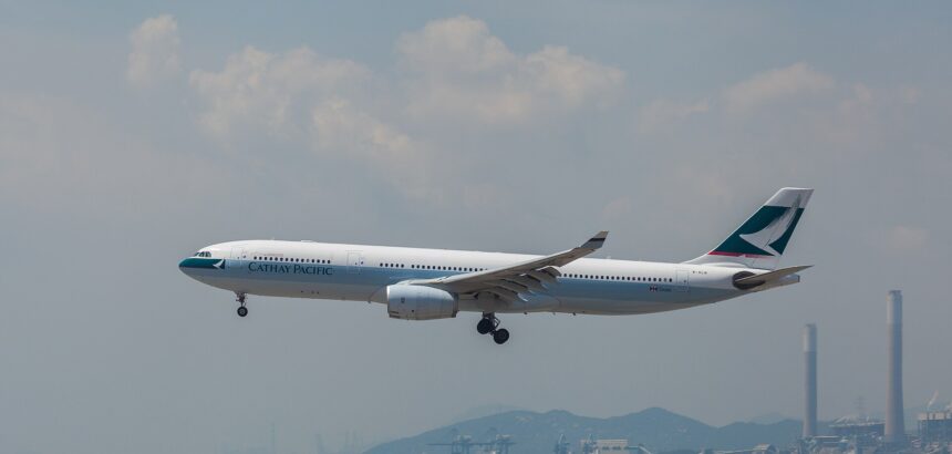 A Cathay Pacific Airbus aircraft taking off at Hong Kong International Airport. Cloudy sky in the background.