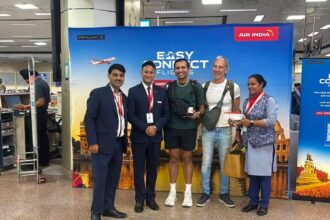 Customers stand with Air India staff to greet the press as part of the Air India 'Easy Connect' service via Amritsar.