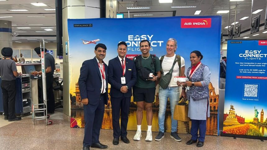 Customers stand with Air India staff to greet the press as part of the Air India 'Easy Connect' service via Amritsar.
