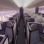 Aeroplane interior aisle view, with rows of Business class seats on either side