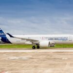 A side view of an Airbus A220-300 aircraft on the ground. Both its landing gear and engines can be seen.