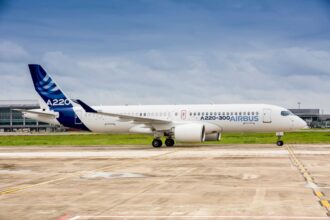A side view of an Airbus A220-300 aircraft on the ground. Both its landing gear and engines can be seen.