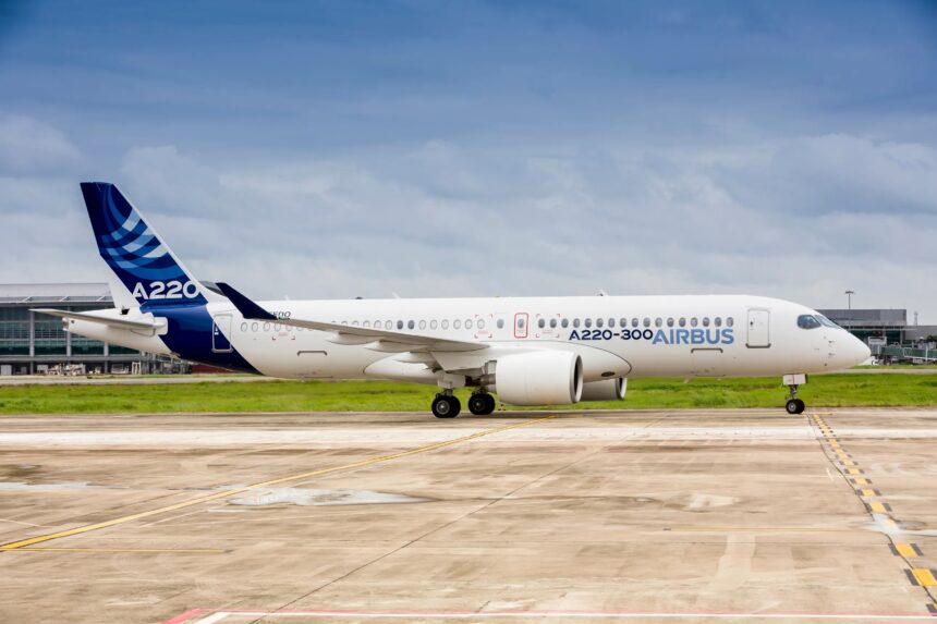 A side view of an Airbus A220-300 aircraft on the ground. Both its landing gear and engines can be seen.