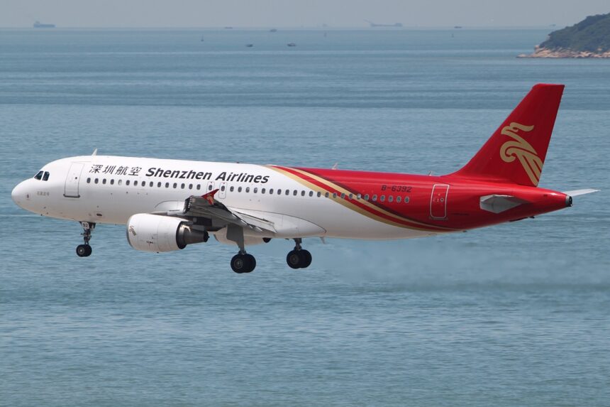 A Shenzhen Airlines Airbus A320 coming in to land with its landing gear out. The sea visible in the background.