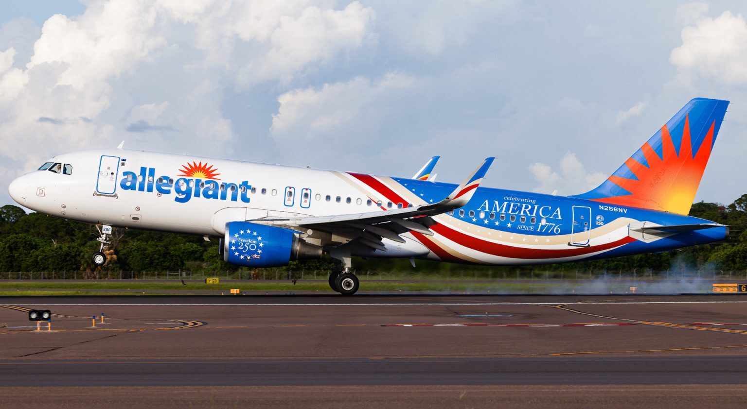 Allegiant Air new livery, white and blue fuselage with beige and red wavy stripes with "America" written on the side. A yellow/red sun on the tail.