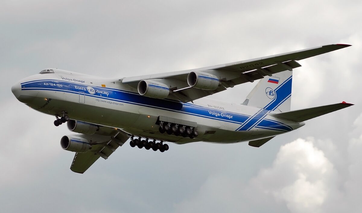 A low-angle view of an Antonov An-124-100 cargo aircraft in flight, showing its extended landing gear, four turbofan engines and distinctive oversized fuselage against the sky