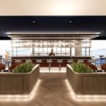The British Airways' redesigned Newark lounge. A bar in the middle with booths on both sides.