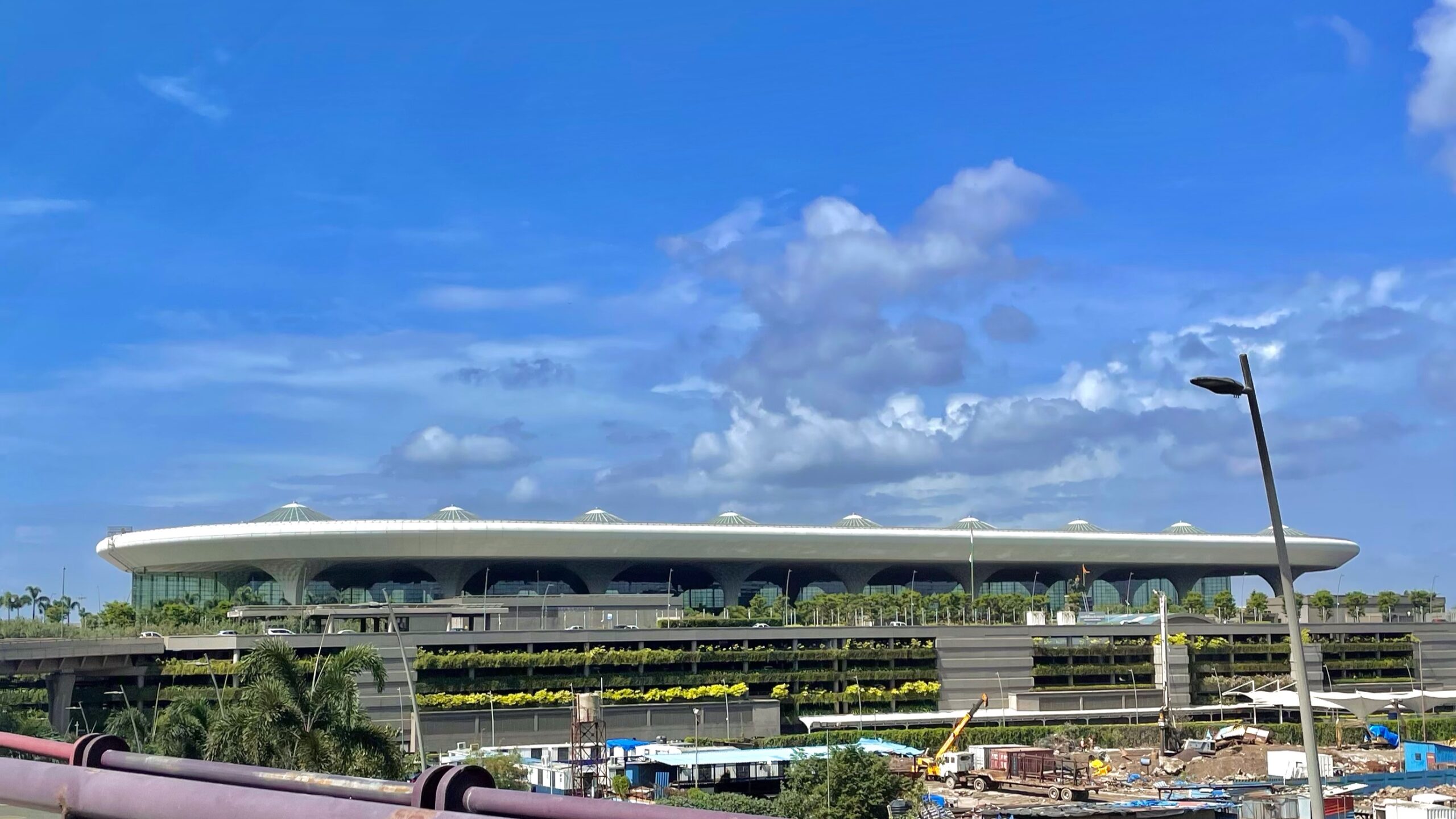 Aerial view of Chhatrapati Shivaji Maharaj International Airport's domed terminal building under a blue sky