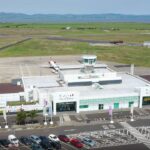 A drone image of the City of Derry Airport (LDY), facing the entrance of the airport. The carpark can be seen at the front, with the runway visible behind the small terminal.
