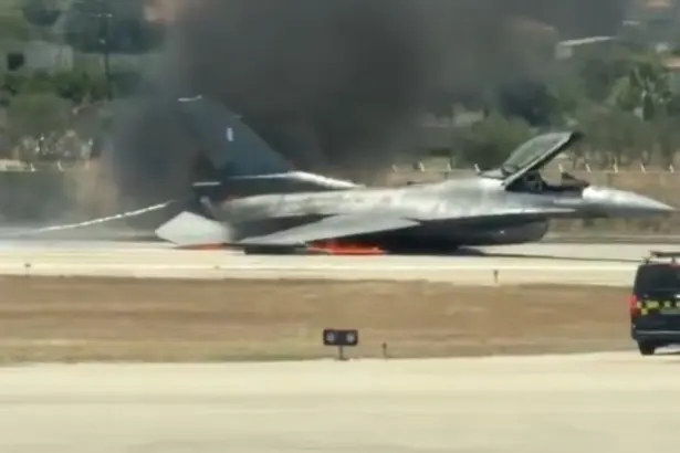 image of the fighter jet crash landed on the runway with smoke and flames coming out from its underside. Emergency response teams heading quickly to the situation.
