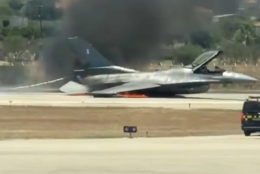image of the fighter jet crash landed on the runway with smoke and flames coming out from its underside. Emergency response teams heading quickly to the situation.