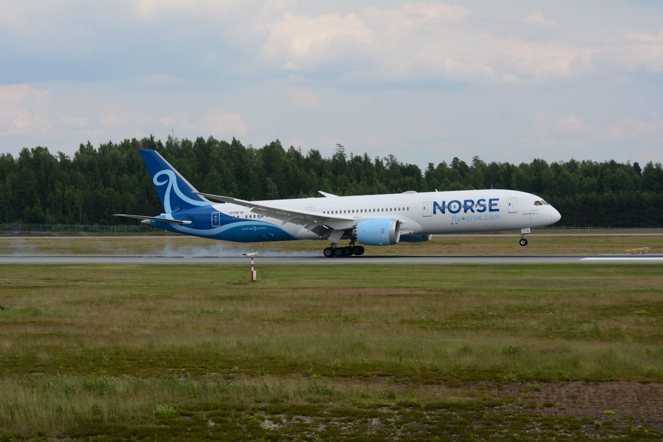 Norse Atlantic Boeing 787-9 Dreamliner registration LN-FNB touching down on a runway surrounded by trees.
