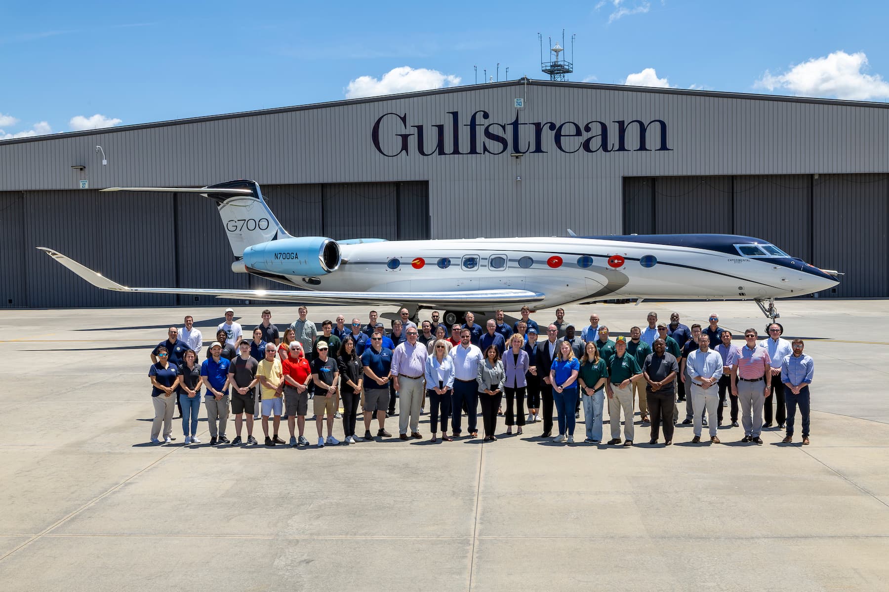 Image shows a silver Gulfstream 800 aircraft in front of a Gulfstream labelled hangar in the background, with a team of people nearby in the foreground.