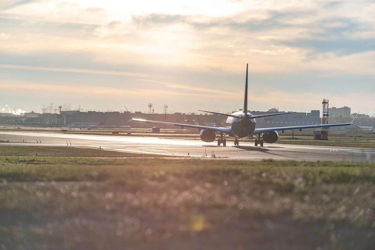 An image of an aircraft on a runway with the sun in the background setting