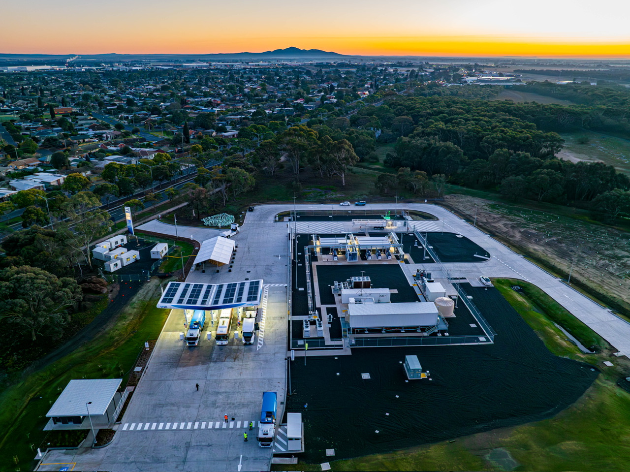 An aerial shot of a Viva Energy hydrogen charging facility at sunset. Two lorries and a bus can be seen being refuelled.