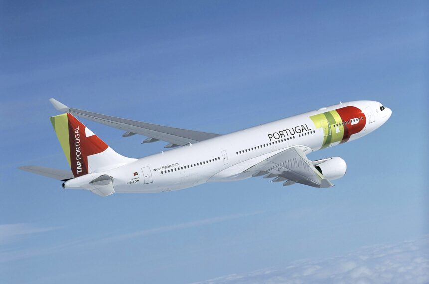 A TAP Air Portugal jet flying upwards in front of a cloudy sky.