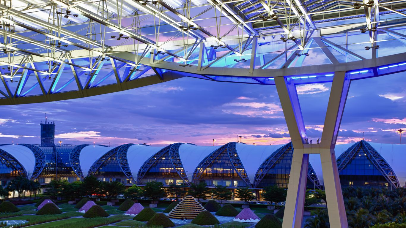 Bangkok Suvarnabhumi (BKK) Airport at sunset, in front of a dark purple sky.