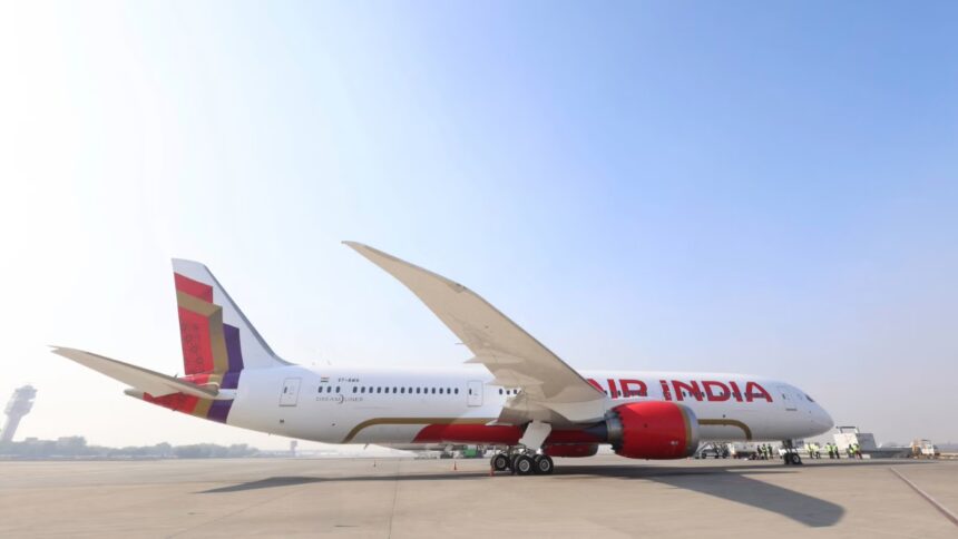 A red and white Air India Boeing 787-9 sat on a runway in front of a clear blue sky on a sunny day.