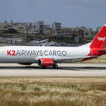 K2 Airways Boeing 737-400F on the runway with buildings in the background.