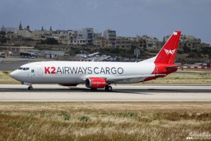 K2 Airways Boeing 737-400F on the runway with buildings in the background.
