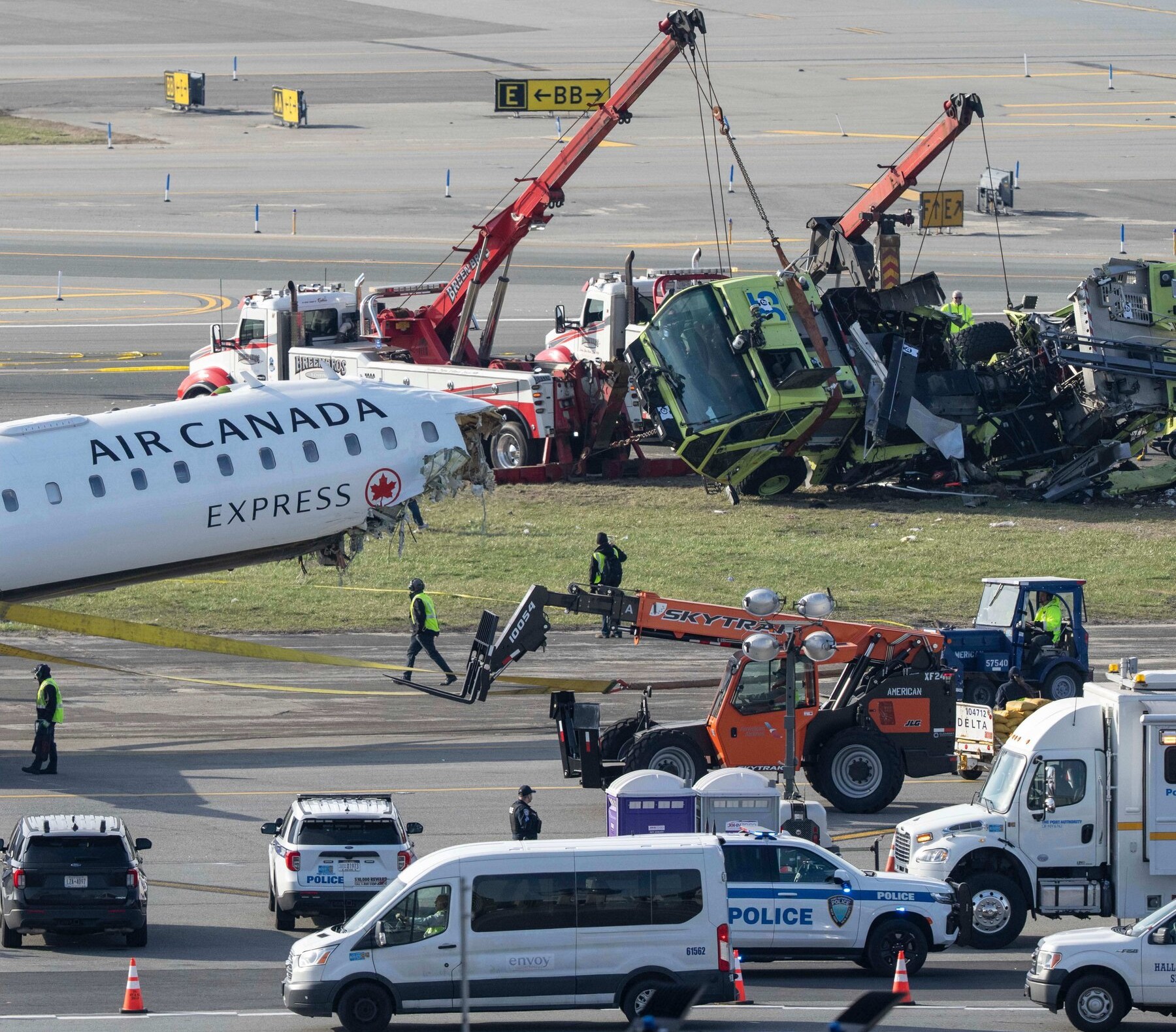 An image of Air Canada aircraft and fire truck wreckages being removed by airport maintenance crew. 